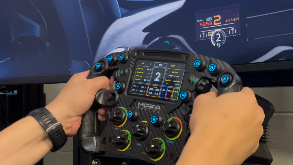 Person using a Moza FSR racing simulator steering wheel with digital displays and controls at TracksVR virtual racing.