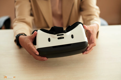 Woman sitting at a desk holding a VR headset