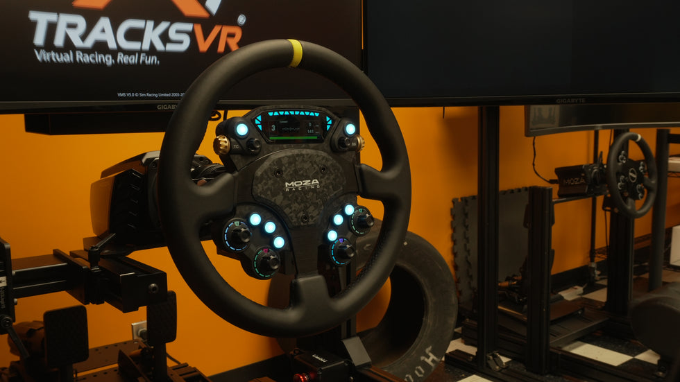 A Moza CS Pro Steering Wheel attached to a racing simulator, with the Moza CS V2P seen in the background. 